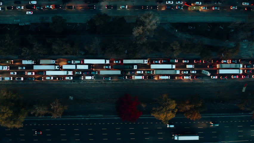 Traffic congestion on a busy city highway with moving vehicles and vibrant autumn foliage in the surrounding area