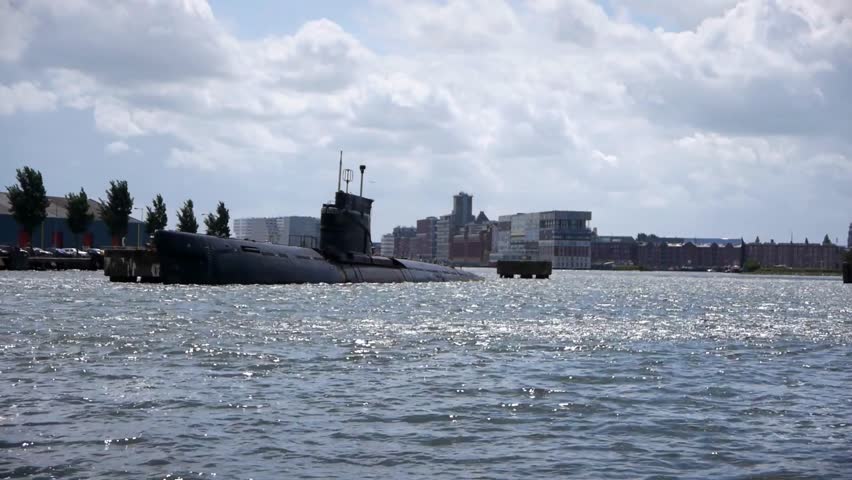 Submarine docked in a harbor in Amsterdam, showcasing naval engineering, maritime operations, and military vessels in an urban port setting.