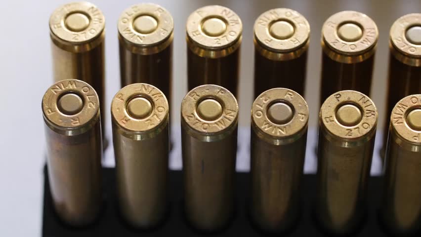 Dolly shot of large-caliber ammunition bullets, highlighting military hardware, firepower, and detailed close-up of tactical munitions in motion.