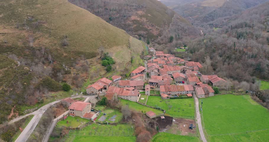 Slow cinematic aerial shot approaching Barcena Mayor, one of the oldest and most beautiful villages in Spain. The footage captures the rustic stone buildings.