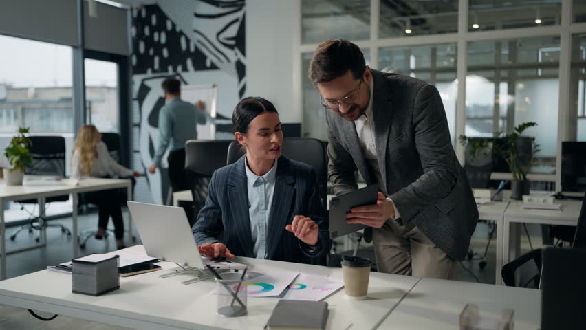 Caucasian businesswoman company leader boss consulting businessman manager showing digital tablet data asking help business man and woman discussing portable wireless computer tasks two office agents