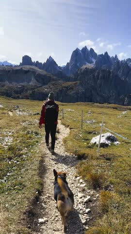 Following hiker with dog walking toward parking area after mountain trek.

Final moments of hiking adventure in Dolomites landscape.