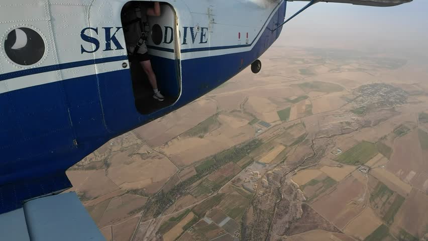 Man jumps out of a plane with a parachute.