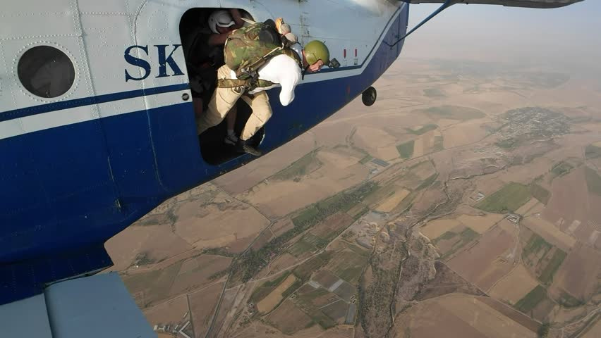 Man jumps out of a plane with a parachute.