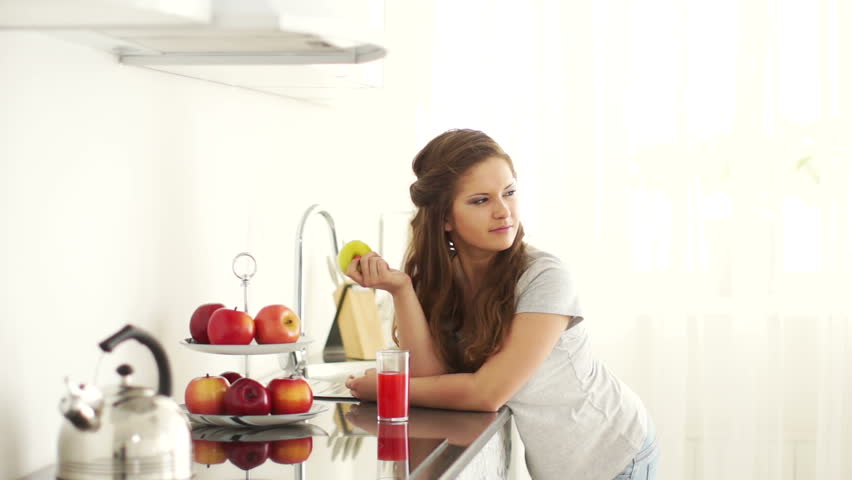 Girl standing in kitchen and holding an apple
