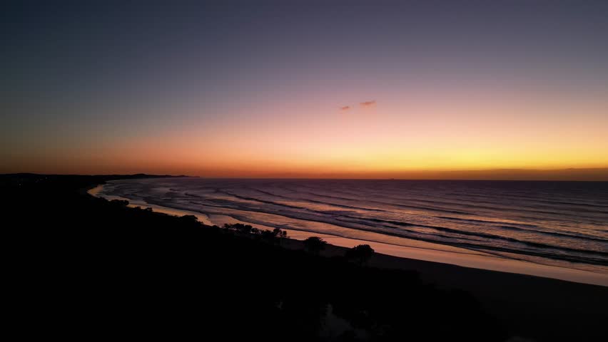 Sunrise over Pacific Ocean waves and curving Bonny Hills coastline, Australia