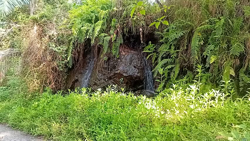 a small waterfall located next to the road in the countryside