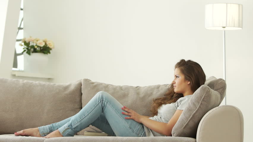 Girl resting on sofa and smiling at camera
