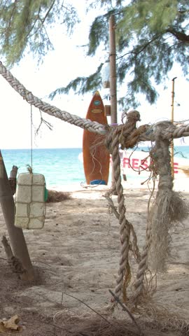Static shot of weathered ropes and styrofoam floats hanging before a turquoise tropical ocean