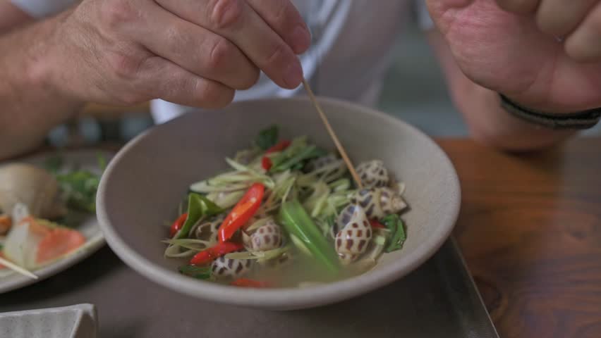 Casual Hands Preparing Spicy Noodles. Focused Shot Of Hands Stirring Spicy Herbs And Noodles Together. Detailed View Of Hands Mixing Flavorful Snails With Chili And Fresh Herbs For Salad