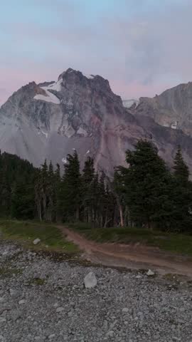 Discover a majestic mountain landscape with snow-capped peaks, evergreen forest, and a winding trail in British Columbia, Canada.