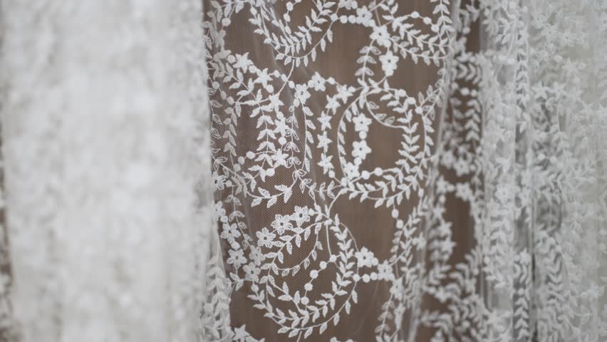 Detailed close up of delicate white lace with floral embroidery on sheer wedding dress fabric soft texture and elegant bridal design