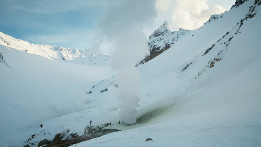 Steam vent rising in snowy alpine valley, overview