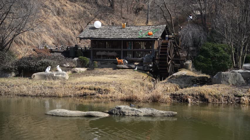 Traditional wooden waterwheel house and statues by the pond