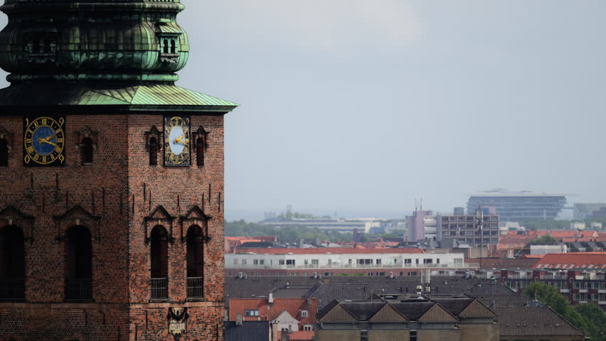 Church clock tower made of brick and copper overlooking city roofs and buildings. Copenhagen, Denmark