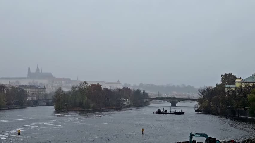 Panoramic view of St. Vitus Cathedral and Vltava River in Prague, Czech Republic in fog. The tram goes over the bridge.