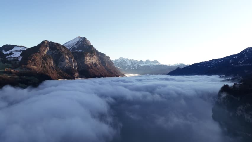 Rocky alpine cliffs and mountains above cloud inversion Switzerland
