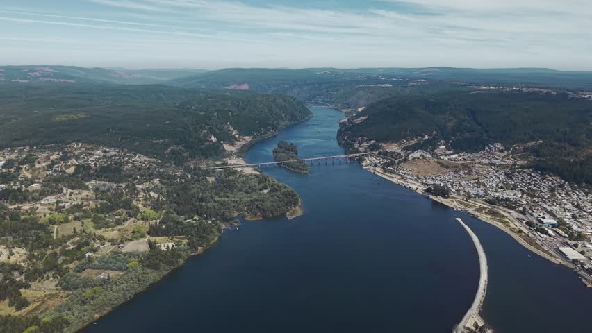 Aerial view of bridge and river mouth where the Maule meets the Pacific, with water channels and shoreline visible from above Chile, 4K