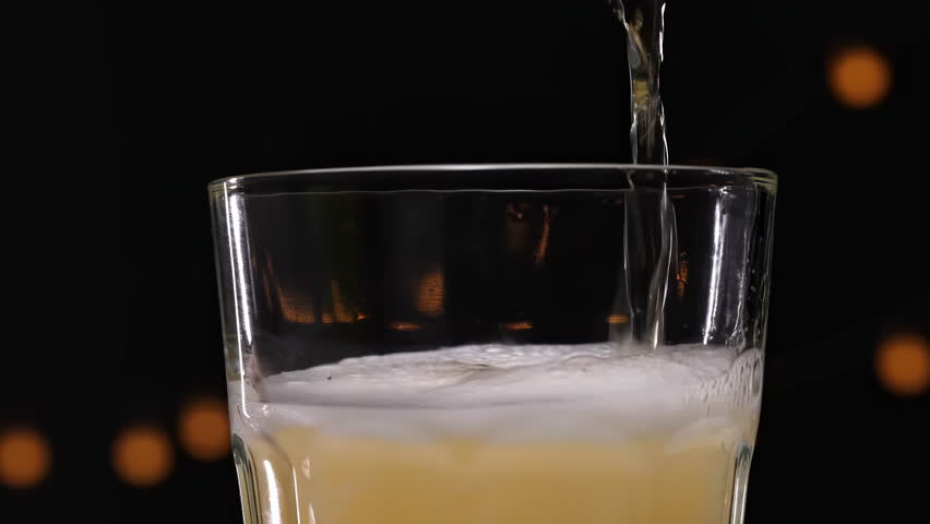 A freshly poured pint of golden beer, creating a thick, frothy, foamy white head that overflows the glass rim, in a cozy pub setting. Perfect for advertisements and refreshing drink