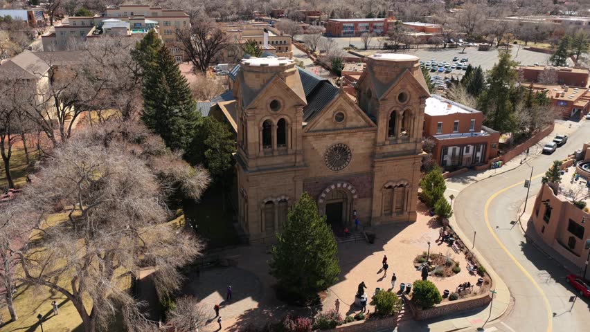 A high-angle drone perspective reveals the grand Romanesque architecture of the iconic Santa Fe Basilica. This 4K shot captures the historic heart of New Mexico’s capital city.