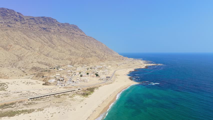 Aerial view of a coastal settlement and mountains bordering turquoise water along the Gulf of Aden in the Car Madow region of Somalia.