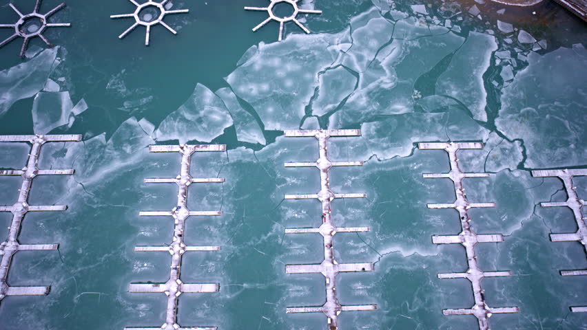 Aerial winter drone view of ice-covered harbor along Lake Michigan beside downtown Chicago Loop skyline.