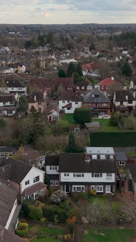 Vertical drone ascent over Bengeo, Hertfordshire looking south toward Hertford, revealing suburban homes, gardens, streets and winter trees under overcast skies in England, UK.