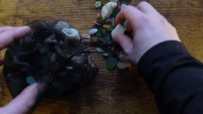 Hands picking and examining sea glass, shells and pebbles scattered on the table - Powered by Shutterstock - Get 15% off with code: PIKWIZARD15