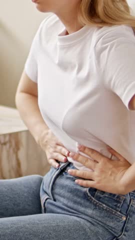 Woman suffering from stomach ache. Holding belly and feeling abdominal menstrual pain or bowel and digestion problems.
