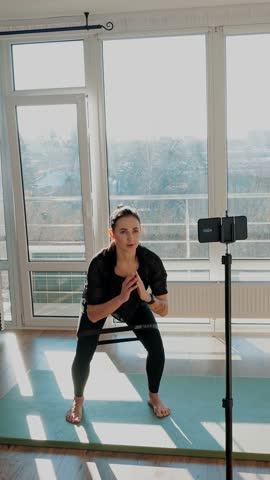 Female fitness coach showing exercises online using smartphone. fitness during lockdown. young woman doing sports at home. concept of fitness, wellness and healthy lifestyle