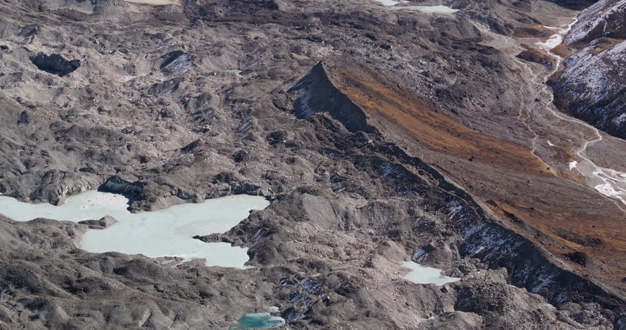 A tilt shot revealing glacier ponds forming on Imja Glacier and Imja Glacier Lake beneath the Himalayan mountain range in Nepal’s Everest region.