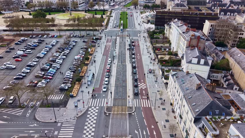 Boulevard du Maréchal Foch with tram and traffic, the Jardin du Mail park, and City Hall in Angers, France. Aerial forward tilt-up reveal