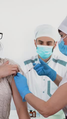 Coronavirus vaccination. nurse or doctor in protective mask and medical gloves, injects vaccine into patient