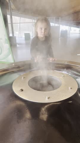 A girl enjoys exploring an interactive steam exhibit at a science museum.