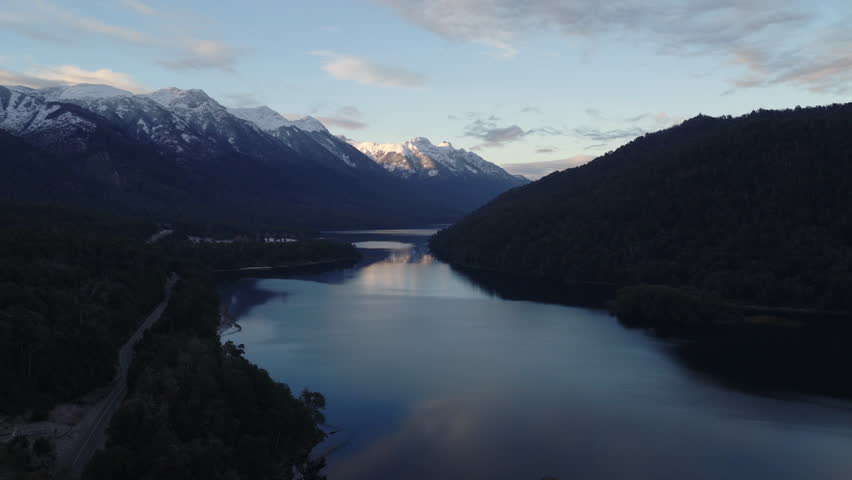 Nahuel Huapi Lake in the North Patagonian Andes near Villa La Angostura, Neuquen Province, Patagonia Argentina with Ruta Nacional 40 running along shoreline beneath snow covered mountains, pull away