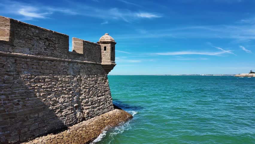 Stone defensive walls of a historic seaside fortress in Cádiz, Spain overlooking the Atlantic Ocean. Coastal fortification and watchtower reflect the city’s rich maritime history and architecture.