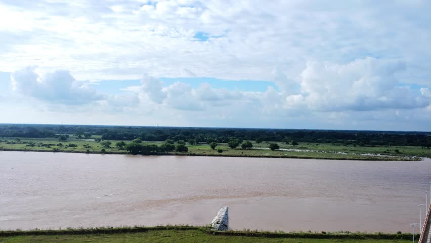 Aerial View of Wide River Under Dramatic Cloudy Sky Landscape. Large River and Green Countryside Under Cloudy Sky. Floodplain River and Distant Green Countryside.