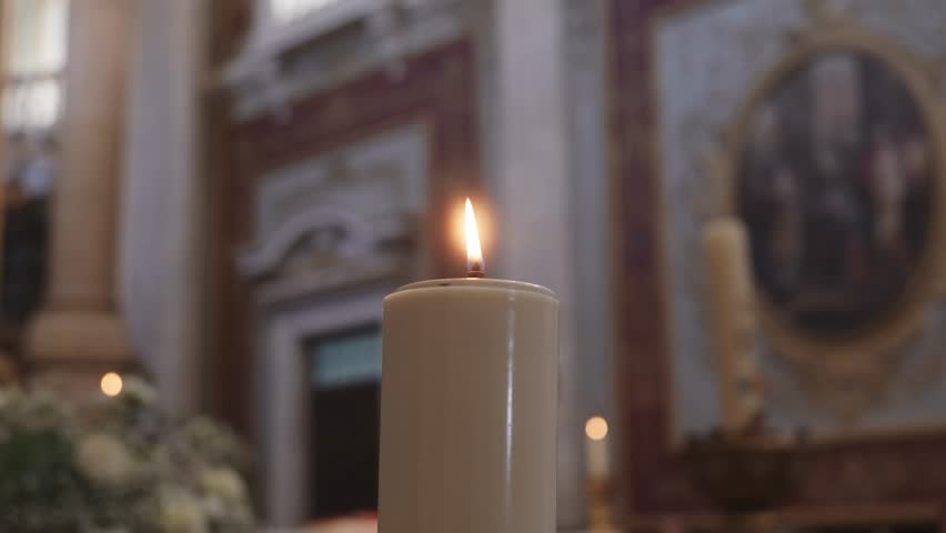 Burning candle with flame inside church during religious service