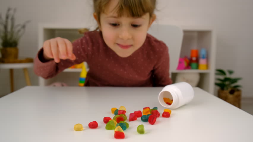 A child eats vitamin gummy bears. Selective focus.