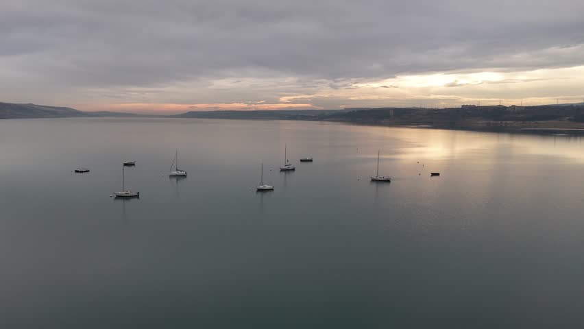 Aerial view of several sailboats moored on a tranquil lake during a beautiful, cloudy sunset