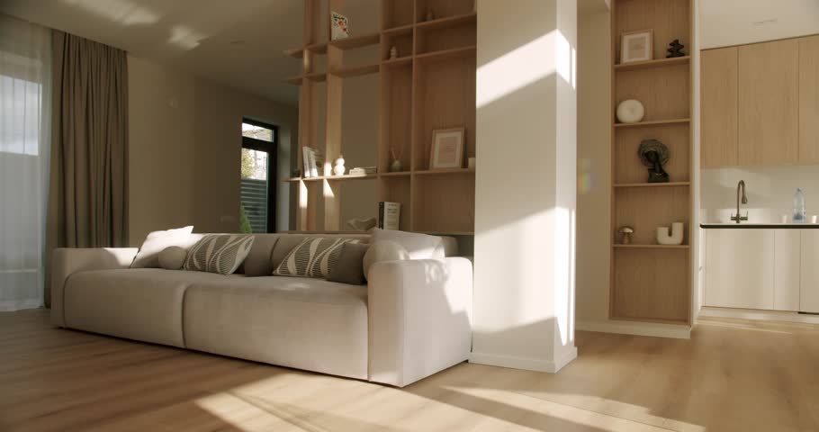 Beautiful morning sunlight moving across a cozy living room with a comfortable sofa and a modern kitchen, creating a peaceful and serene atmosphere in a contemporary Scandinavian-style interior