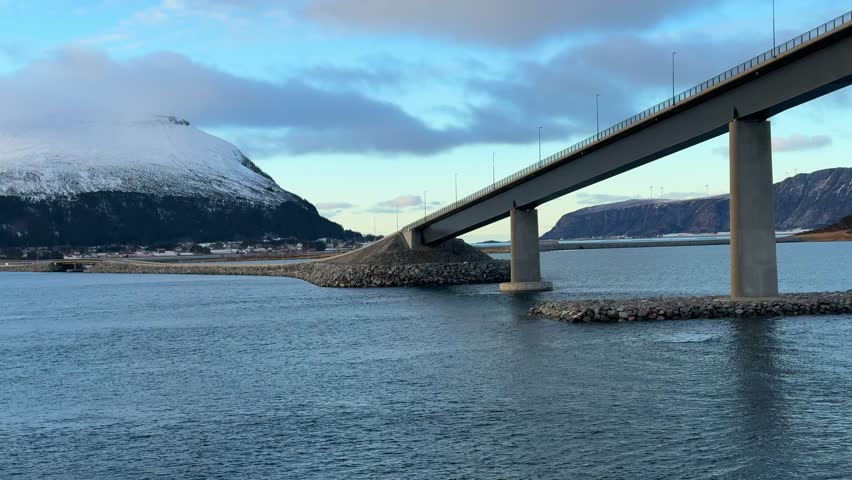 View of bridge over water with mountains in the background on a cloudy day in Norway