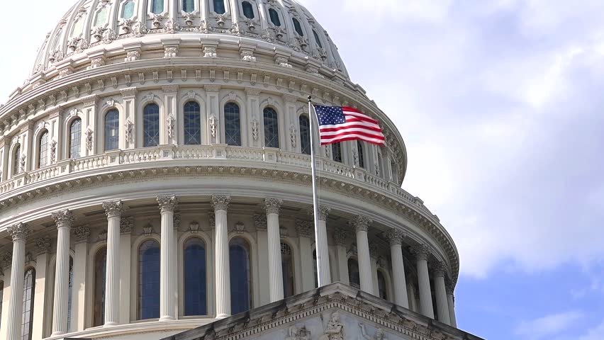 close-up of the Capitol dome in Washington, D.C., with a flag waving.
