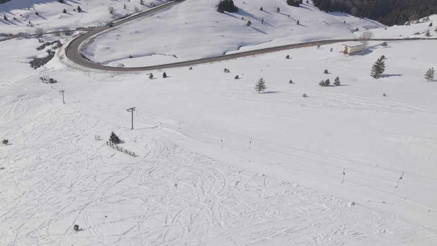Aerial forward tracking shot over a snow-covered ski resort and mountain road at Uludag