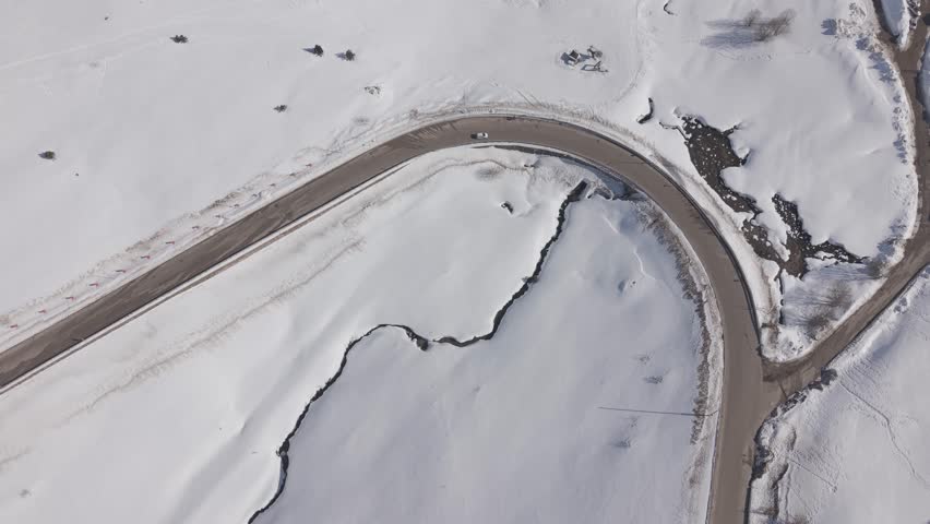 Aerial forward tracking shot over a snow-covered ski resort and mountain road at Uludag