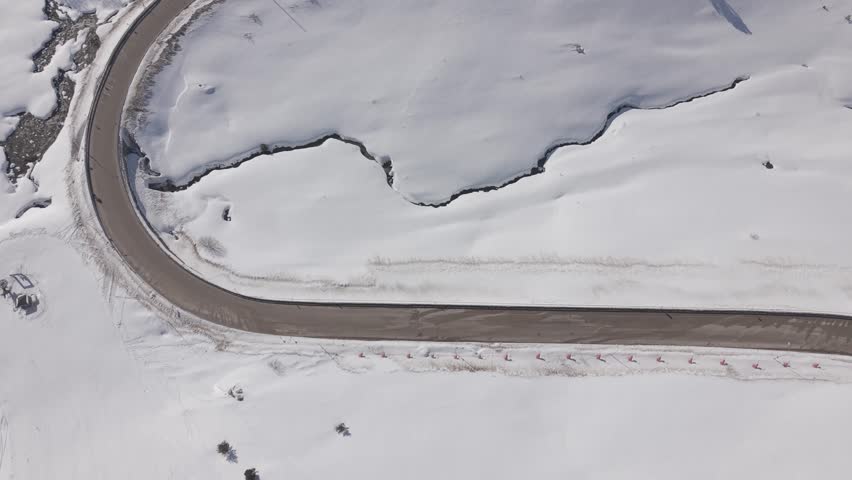 Aerial forward tracking shot over a snow-covered ski resort and mountain road at Uludag