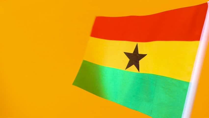 This vibrant video features the national flag of Ghana waving gracefully against a solid, bright yellow background. The flag’s iconic horizontal stripes of red, gold, and green are prominently displayed, with the five-pointed Black Star centered in the gold band. The camera captures the rhythmic motion of the fabric, highlighting its texture and the symbolic Pan-African colors. The composition is clean and focused, celebrating Ghanaian identity, independence, and national pride.