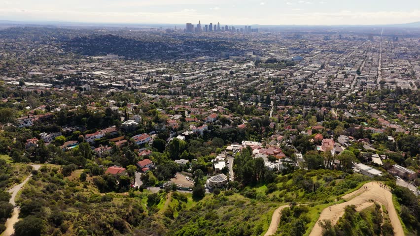 Los Angeles aerial view of residential hills with downtown skyline in distance drone shot