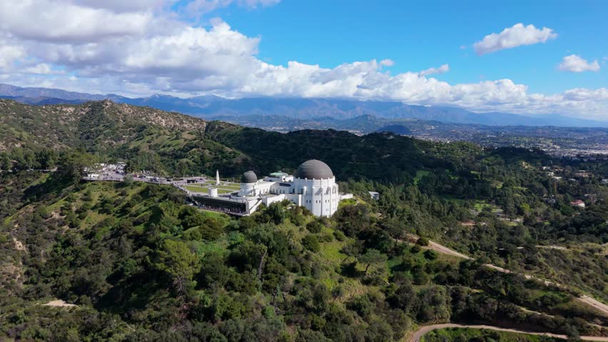 Griffith Observatory aerial view on hilltop with mountains and clouds Los Angeles California