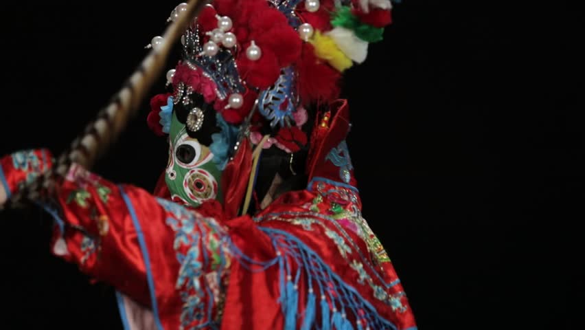 Sichuan Opera mask changing performance, dramatic traditional Chinese art on black background.